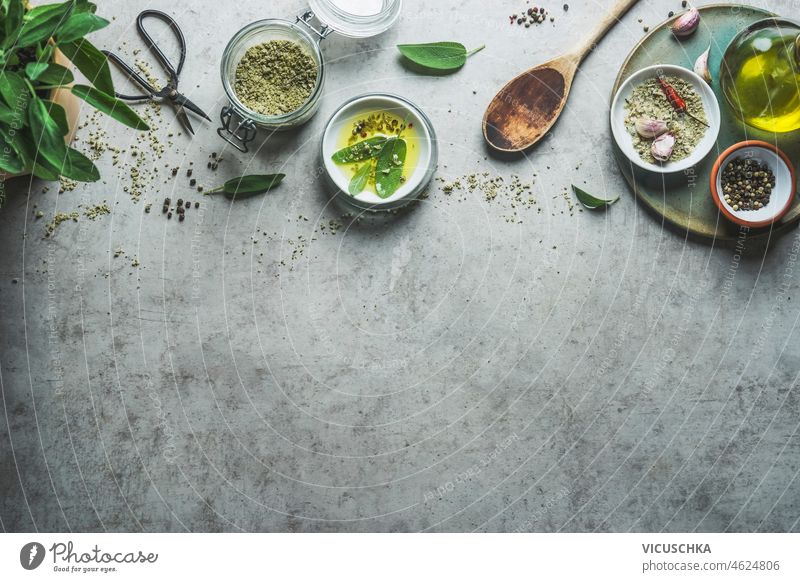 Gewürzhintergrund mit Kräutern, Gewürzen, Kräutersalz, Olivenöl und Holzlöffel zum schmackhaften Kochen. Hintergrund Geschmack Küchenkräuter Kräuterbuch Salz