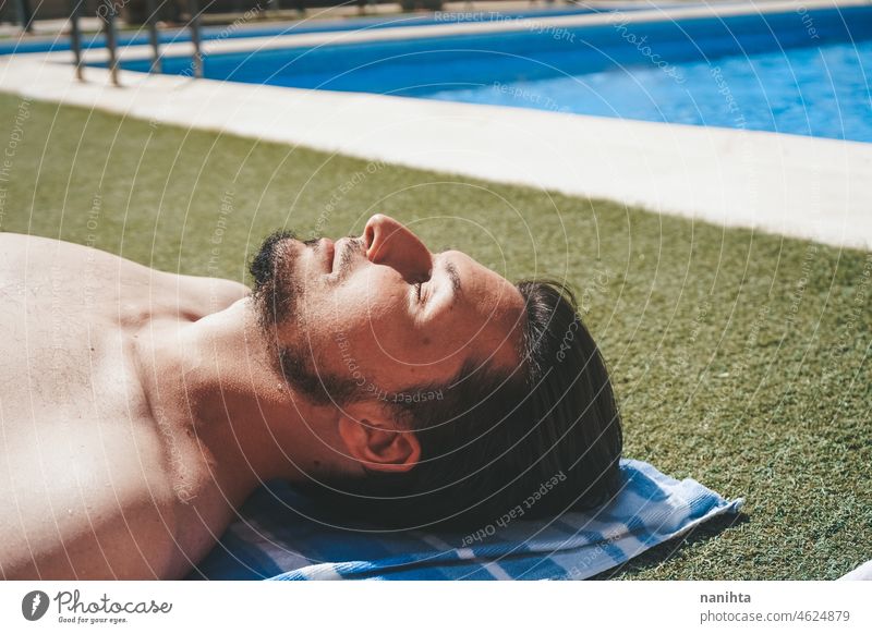 YOung Mann genießt ein Sonnenbad am Schwimmbad Haut sich[Akk] entspannen Pool männlich Feiertage Sommer Sommerzeit ansteckend Risiko Schutz Grippe grün Gras