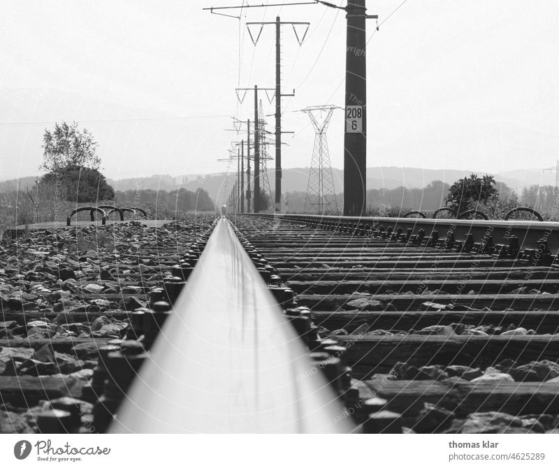 Eisenbahnschiene mit Strommasten in Schwarz weiß strommast Schwarz/Weiss steine verkehr umwelt klima land