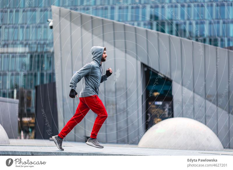 Junger Mann beim Laufen in der Stadt Menschen kalte Witterung Herbst Sportler Stärke Motivation Tatkraft eine Person Bodybuilding Energie gutaussehend
