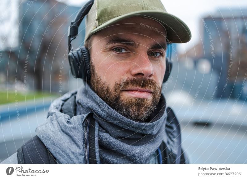 Porträt eines jungen Mannes mit Kopfhörern, der im Freien Musik hört Menschen kalte Witterung Herbst Sportler Stärke Motivation Tatkraft eine Person