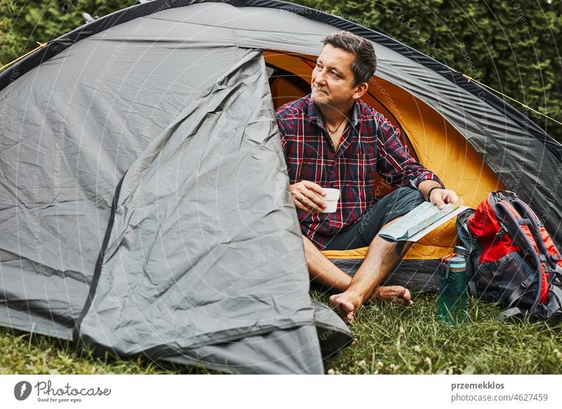 Mann entspannt sich im Zelt beim Camping im Sommerurlaub. Mann hält Karte bei der Planung der nächsten Reise Urlaub Ausflug Abenteuer Campingplatz reisend Lager