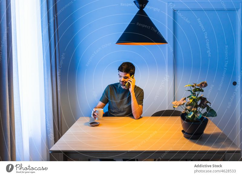 Mann spricht am Tisch mit Smartphone freiberuflich Telefonanruf Gespräch Pause diskutieren Kommunizieren heimwärts reden sprechen Apparatur männlich Blume