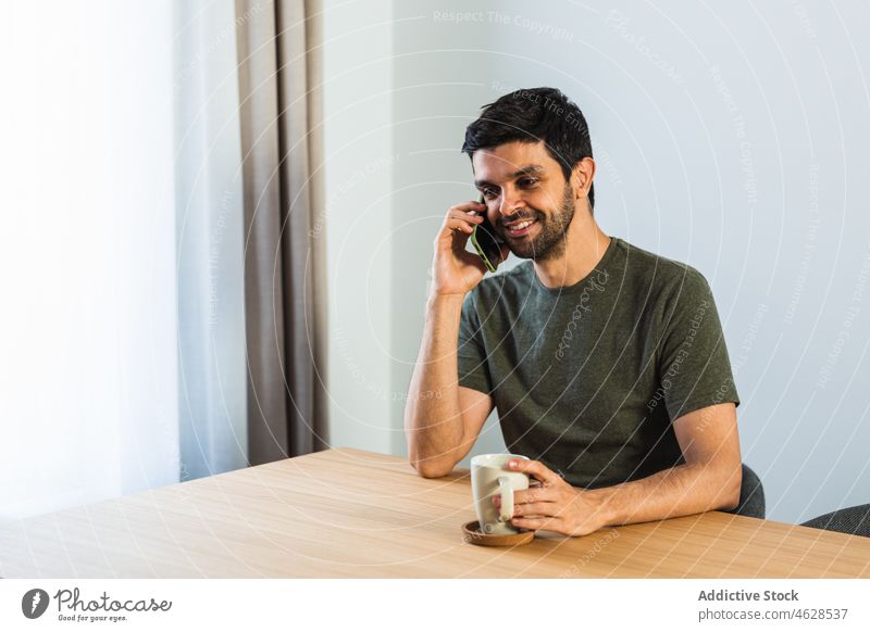 Mann spricht am Tisch mit Smartphone freiberuflich Telefonanruf Gespräch Pause diskutieren Kommunizieren heimwärts reden sprechen Apparatur männlich Blume