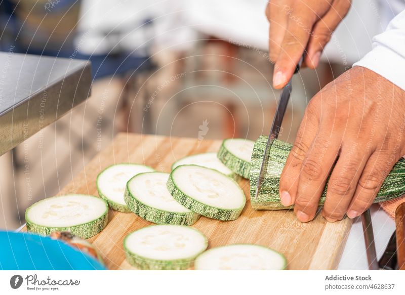 Ein Mann schneidet reife Zucchini mit einem Messer auf einem Schneidebrett geschnitten Koch vorbereiten Küche Lebensmittel Gemüse frisch hacken Scheibe