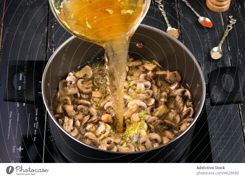 Brühe in die Pfanne mit den Pilzen gießen Suppe Herd Koch Topf Küche kulinarisch selbstgemacht eingießen vorbereiten Prozess Kocher Vorrichtung heimwärts