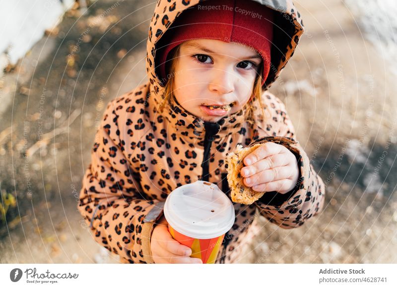 Nettes Mädchen mit Getränk zum Mitnehmen an einem Wintertag Kind Keks Imbissbude Heißgetränk Straße Großstadt kalt Kindheit Dessert trinken Oberbekleidung