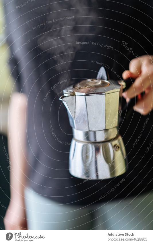 Anonyme Person mit Moka-Kanne Moka-Topf Kaffeemaschine Geysir Küche brauen Vorrichtung modern Heißgetränk Gerät rostfrei Stahl Metall Licht heimisch