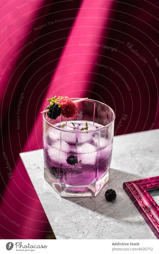 Glas Brombeer-Cocktail mit Eiswürfeln Brombeeren purpur Erfrischung Himbeeren Kristalle Getränk Aperitif kalt Zahnstocher Tisch liquide hölzern cool Schnaps