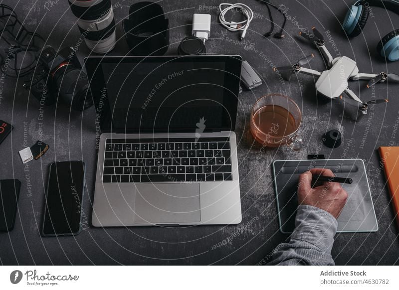 Mann arbeitet an einem Grafiktablett am Arbeitsplatz mit verschiedenen Geräten Fotograf benutzend Tablette graphisch Laptop Griffel Dröhnen Schreibtisch
