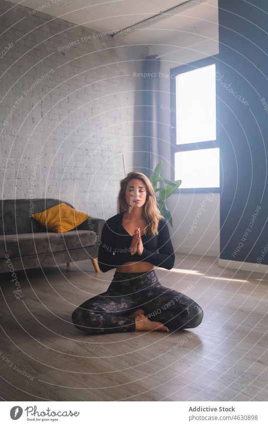 Frau meditiert auf Yogamatte mental meditieren Körperhaltung Atem üben Augen geschlossen Gebetshände gestikulieren Namaste Hände zusammen Energie Stressabbau