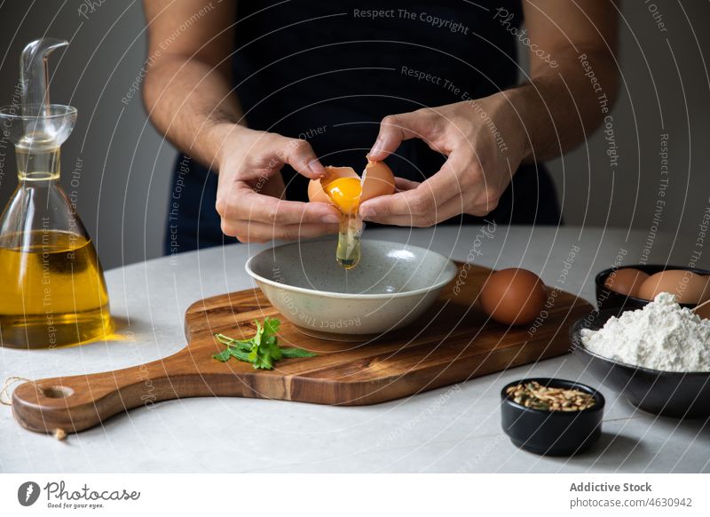 Unbekannter Mann schlägt Ei in Schale Koch kulinarisch Pause Küche Rezept Bestandteil roh Küchenchef vorbereiten Lebensmittel Schneidebrett verschiedene Produkt