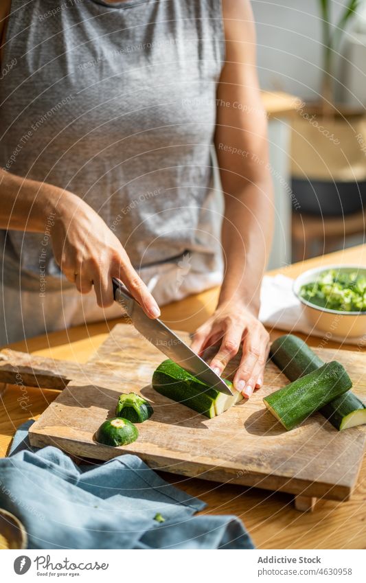 Unbekannte Frau schneidet Gurke in der Küche Salatgurke geschnitten Gemüse Koch kulinarisch Bestandteil Rezept vorbereiten Küchenchef Lebensmittel Produkt Tisch