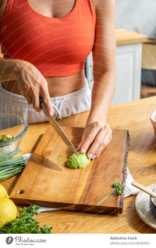 Anonyme Frau schneidet Avocado in der Küche Koch Gemüse gesunde Ernährung Vitamin kulinarisch geschnitten Rezept Bestandteil vorbereiten Küchenchef Lebensmittel