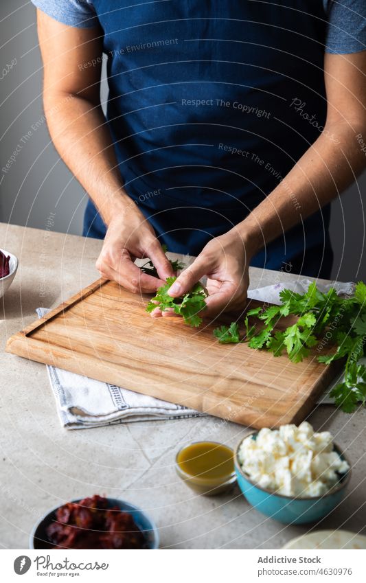 Gesichtsloser Mann, der am Tisch Petersilie zubereitet Kraut Grün Koch kulinarisch Küche Rezept Bestandteil vorbereiten Küchenchef Lebensmittel Produkt