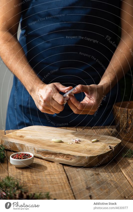 Gesichtsloser Mann, der in der Küche Knoblauch schält sich[Akk] schälen Koch kulinarisch Rezept Bestandteil vorbereiten Küchenchef Lebensmittel Produkt Paprika