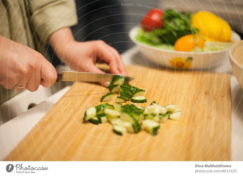 Eine Frau schneidet Gurken und bereitet einen Salat zu - eine gesunde vegane Mahlzeit Veganer Vegetarier gesunde Ernährung Gesunde Ernährung Gesunder Lebensstil