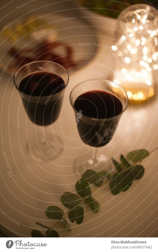 Zwei Gläser Rotwein mit Aperitifs bei einem romantischen Date bei Kerzenschein und festlicher Beleuchtung Wein Glas trinken Alkohol rot Tisch weiß Restaurant