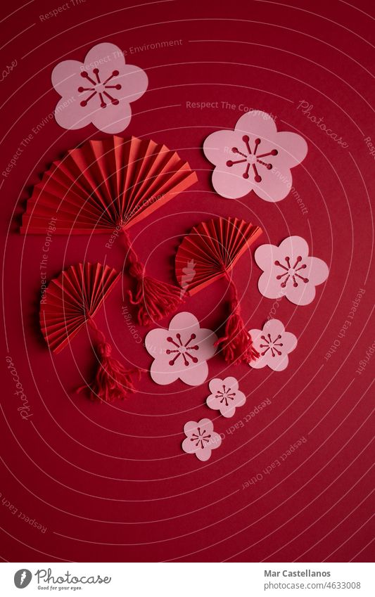 Chinesisches Neujahr. Dekoration mit traditionellen chinesischen Neujahrsmotiven, ausgeschnittene Papierdekorationen auf rotem Kartonhintergrund. Platz zum Kopieren. Vertikales Foto.