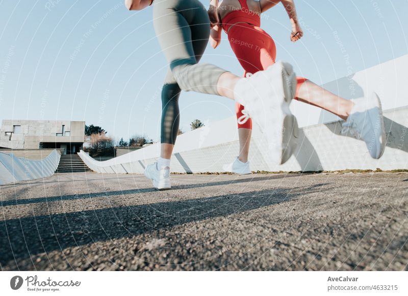 Zwei junge Fitness-Frauen, die im Freien trainieren und Sportkleidung tragen. Fitness-Mädchen trainieren zusammen. Niedriger Winkel Bild bewegen Bewegung Bild. Gesundes Sportleben