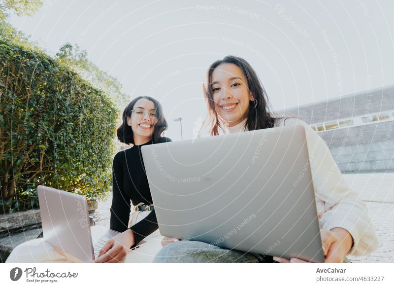 Afrikanisch-arabisches Studentenpaar, das außerhalb des Campus studiert, während es an seinen Laptops arbeitet und lernt, ein Projekt bespricht, das es in der Klasse präsentieren will, in die Kamera schaut und lächelt, zurück zum Klassenkonzept