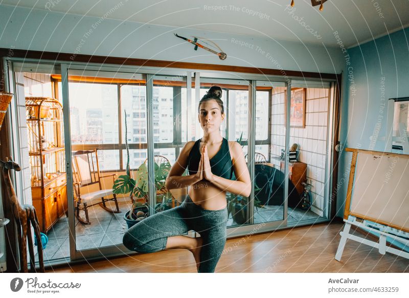Attraktive Fitness junge Frau, die den Baum Pose tun, Yoga mit Online-Kurs zu Hause suchen konzentriert. Unterhaltung und Bildung im Internet. Gesunde Lebensweise Konzept während der freien Zeit.