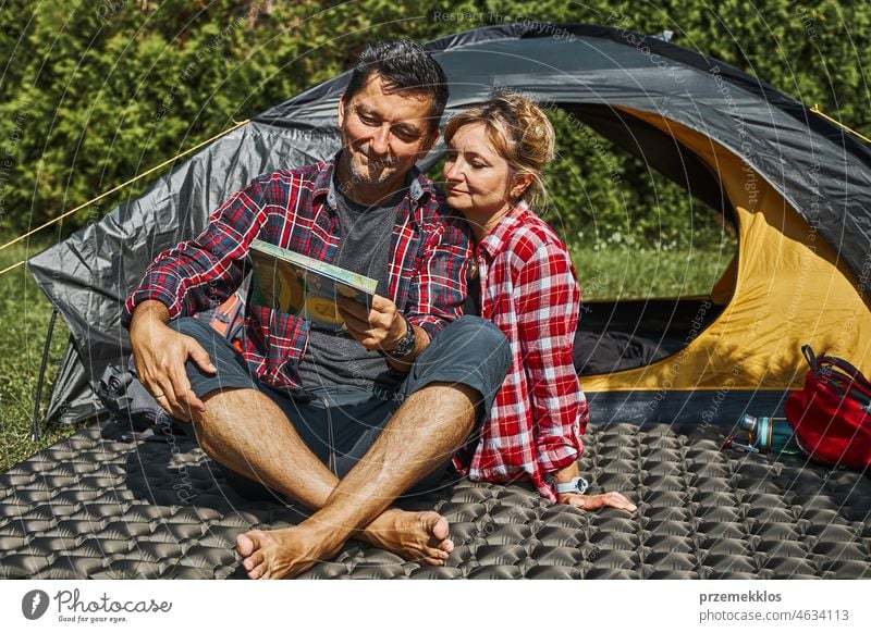 Ein Paar plant seine nächste Reise, während es mit einer Karte am Zelt sitzt. Menschen entspannen auf dem Campingplatz während der Sommerferien Urlaub Ausflug