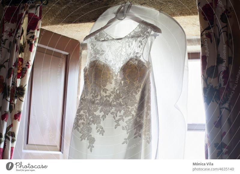 Ein im Fenster hängendes Hochzeitskleid Kleid Braut Liebe Festakt weiß bestickt Gardine