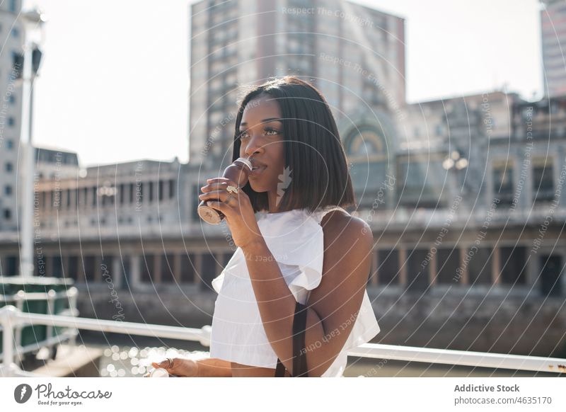 Schwarze Frau genießt Joghurt auf der Straße trinken urban Stil Schokolade Sommer jung schwarz Afroamerikaner ethnisch Getränk trendy Outfit tagsüber Lifestyle