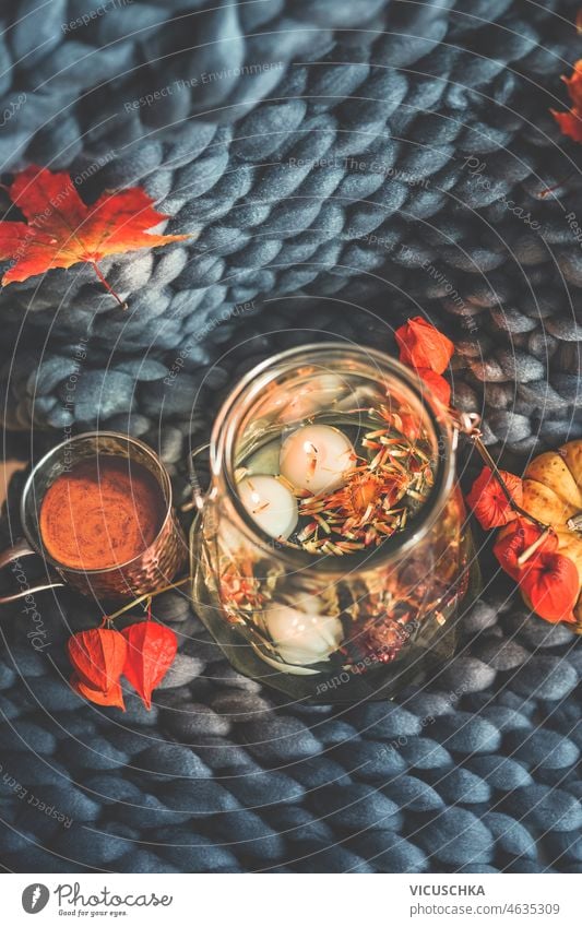 Herbstdekoration mit Wasservase und Schwimmkerzen auf grauer Wolldecke mit Herbstblättern und Kaffee Dekoration & Verzierung Vase fliegend Kerzen Wolle
