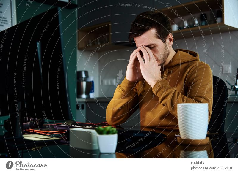 Ein müder Mann arbeitet in der Nacht am Arbeitsplatz Überarbeitung spät Burnout aus der Ferne Stress Kopfschmerzen Büro Fernarbeit pc Computer gelangweilt