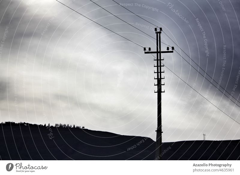 Dramatische Industrielandschaft mit einem Stromleitungsmast am Horizont. Atmosphäre Business Kabel Wolken dunkel Menschenleer verlassenes Gebiet dramatisch