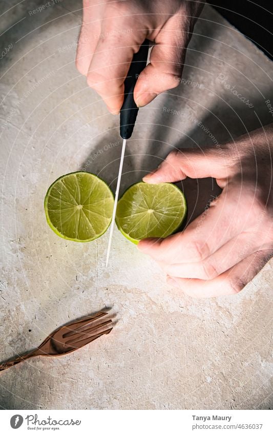 Hände eines Mannes, der eine Limette mit einem Messer halbiert Zitronensaft Gesunde Ernährung Früchte Saft Vitamin Vitamin C Erfrischungsgetränk grüne Zitronen