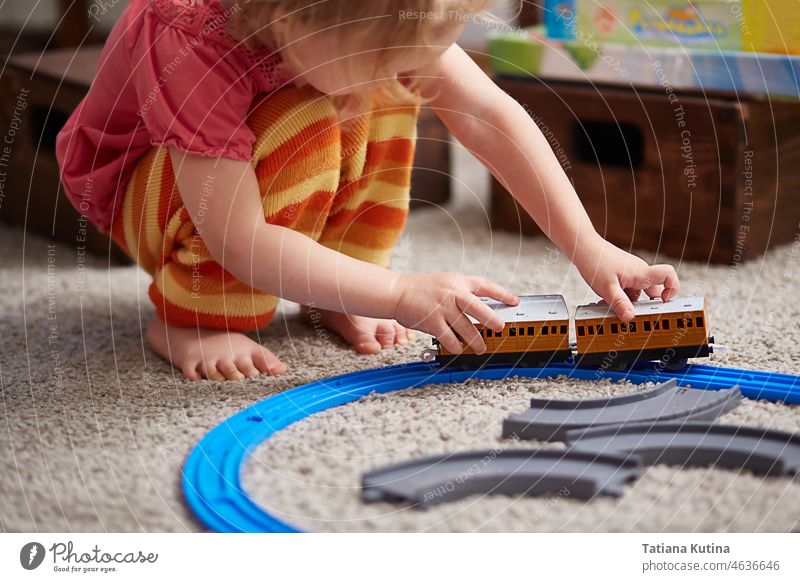 Mädchen spielt mit einer Eisenbahn. Lernspielzeug für Kinder im Vorschul- und Kindergartenalter. Ein Mädchen baut eine Spielzeugeisenbahn zu Hause oder im Kindergarten