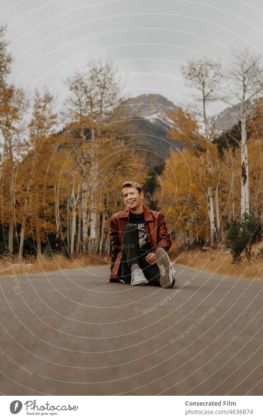 Teenager, der mitten auf der Straße in den Bergen von Colorado sitzt Farbe fallen Herbst Laubwerk reisen Abenteuer Stil Mode Männermode Herrenmode Kanada