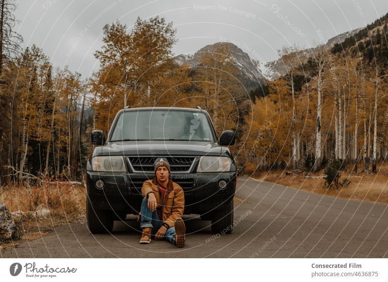 Mann sitzt vor seinem Abenteuerauto in den Bergen reisen PKW Wunder Fahrzeug Abenteuer Auto Jeep Berge u. Gebirge Bergfahrzeug Reisefahrzeug Herrenmode