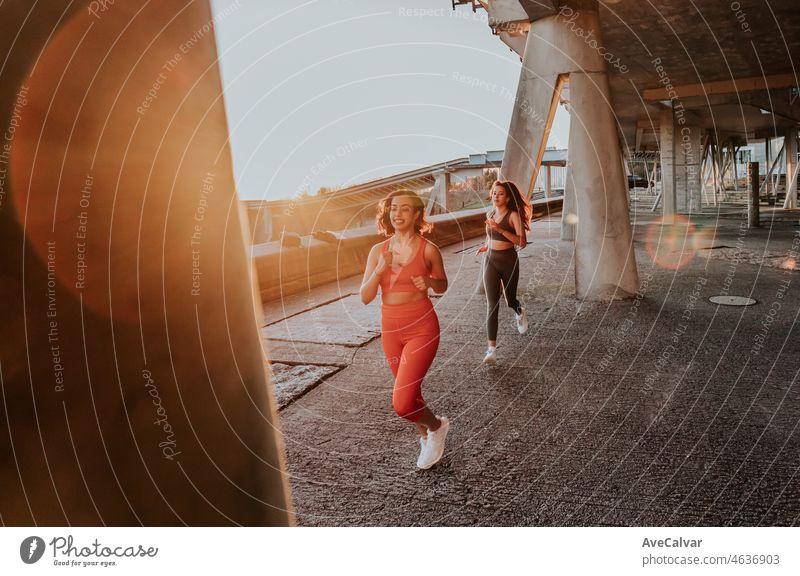 Zwei junge sportliche afrikanische Frau läuft während des Sonnenuntergangs auf einem städtischen Szenario, harter Kontrast Schatten, joggen während des Sonnenuntergangs. Gesundes Leben neue Gewohnheiten Konzept.Spaß zusammen Bewegung Bild