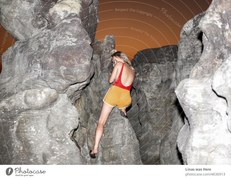 Einige Felsen zum Klettern in Vietnam für dieses hübsche blonde Mädchen. Bekleidet mit einem roten Badeanzug, orangefarbenen Shorts und Hausschuhen ist sie nicht ganz so bereit zum Klettern. Ein schöner Sonnenuntergang Landschaft begleitet sie.