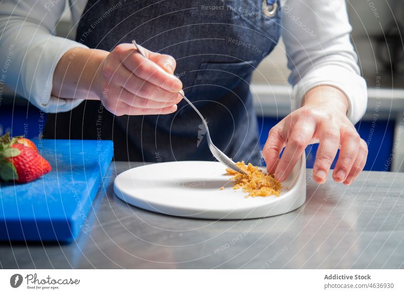 Anonyme Köchin bei der Zubereitung eines Desserts im Restaurant Frau Küchenchef Koch Teller Krümel einrichten kulinarisch Tisch professionell Rezept Uniform