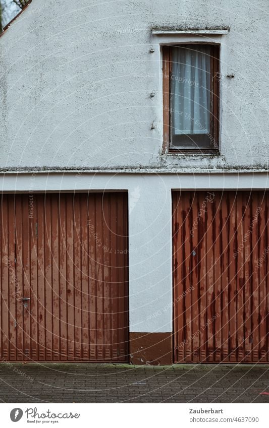 Garagentore und Fenster an Fassade eines älteren Hauses Einfahrt Doppelgarage braun weiß Kleinstadt Gardine alt vergänglich fleckig schäbig Wirklichkeit Gebäude