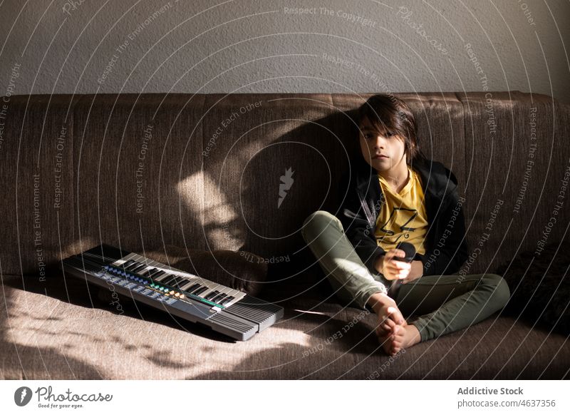 Ethnischer Junge mit Mikrofon neben der Tastatur Kind Keyboard Synthesizer Instrument Kindheit Musical Vergnügen spielen unterhalten Wohnzimmer heimwärts