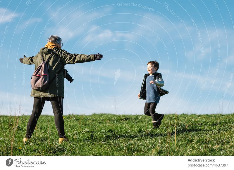 Großmutter streckt die Arme nach dem laufenden Jungen auf dem Rasen aus Enkel Lachen Spaß Natur Arme ausgestreckt Glück Freude heiter sorgenfrei positiv