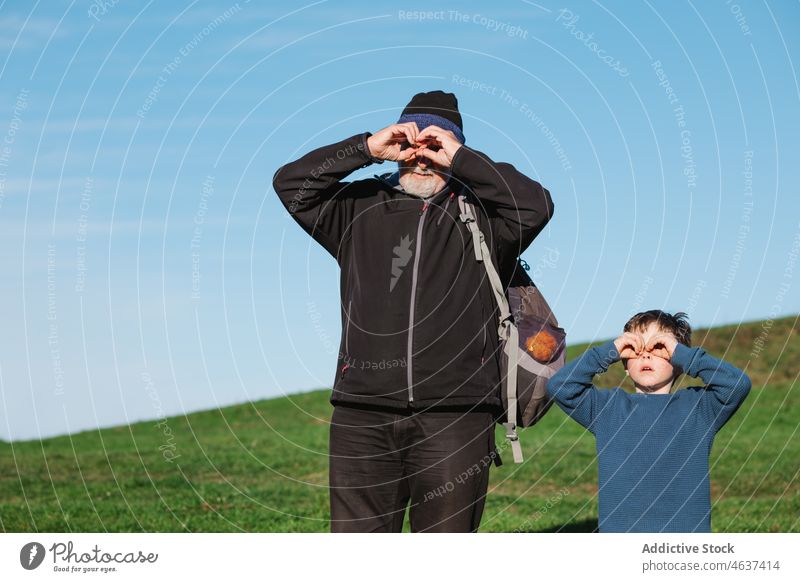 Großvater und Enkel machen eine binokulare Geste in der Natur beobachten Fernglas neugierig gestikulieren zuschauen Fundstück erkunden Junge Mann spionieren