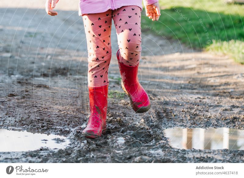 Anonymes Kind steht auf schmutzigem Boden Weg Gummistiefel Schmutz Schlamm Pfütze nass Wasser Straße Kindheit Stiefel dreckig Bürgersteig Farbe Laufsteg hell