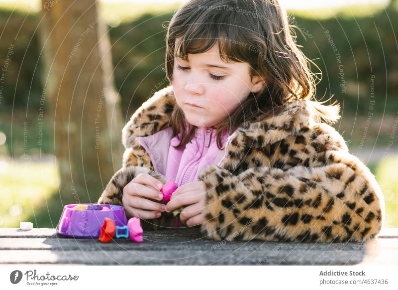 Mädchen spielt mit Spielzeug am Tisch im Park neugierig spielen Interesse Kind Zeit verbringen bezaubernd Oberbekleidung unschuldig sorgenfrei unterhalten
