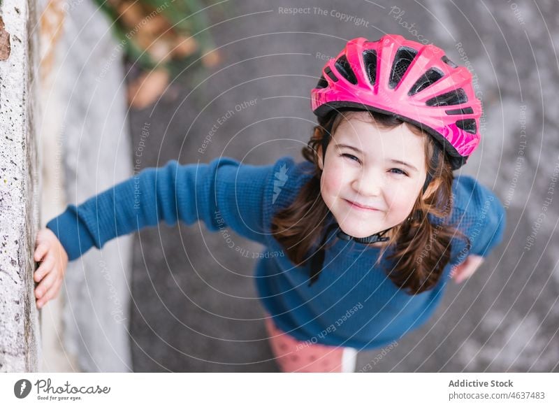 Niedliches Mädchen mit Helm in der Nähe der Grenze Kind Straße Hobby Lächeln Kindheit Freizeit Zeit verbringen Glück Aktivität Borte Barriere üben Sommer Weg