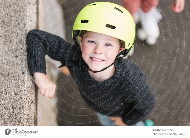 Niedlicher Junge mit Helm in der Nähe der Grenze Kind Straße Hobby Lächeln Kindheit Freizeit Zeit verbringen Glück Aktivität Borte Barriere üben Sommer Weg