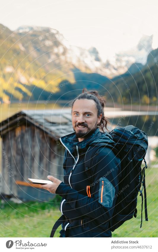 Reisender benutzt Smartphone in der Nähe eines Bergsees Mann Natur Berge u. Gebirge Lächeln See benutzend reisen Backpacker Glück Tourist Österreich männlich