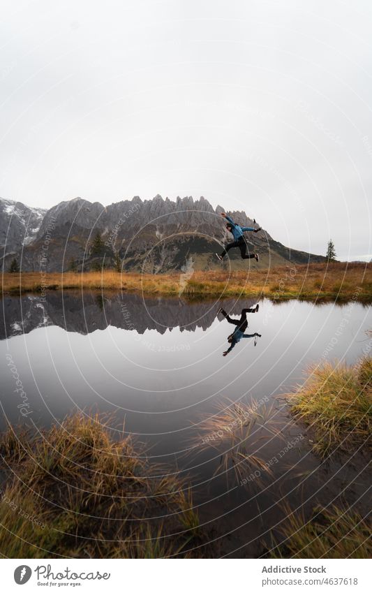 Mann springt in der Nähe von See und Bergen Reisender Berge u. Gebirge Österreich springen Natur Landschaft Ambitus Kamm männlich Ufer Nebel reisen Tourismus
