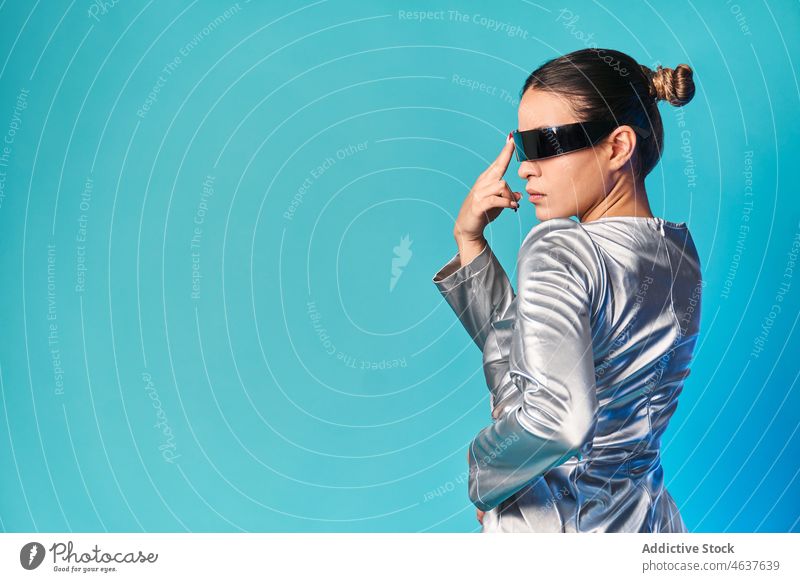Ethnische Frau, die ihr Gesicht berührt, während sie die virtuelle Realität mit einer futuristischen Brille erlebt Gesicht berühren Virtuelle Realität Stil